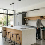Modern minimalist kitchen interior featuring high-end cabinetry and a sleek sensor-operated trash can for odor control.